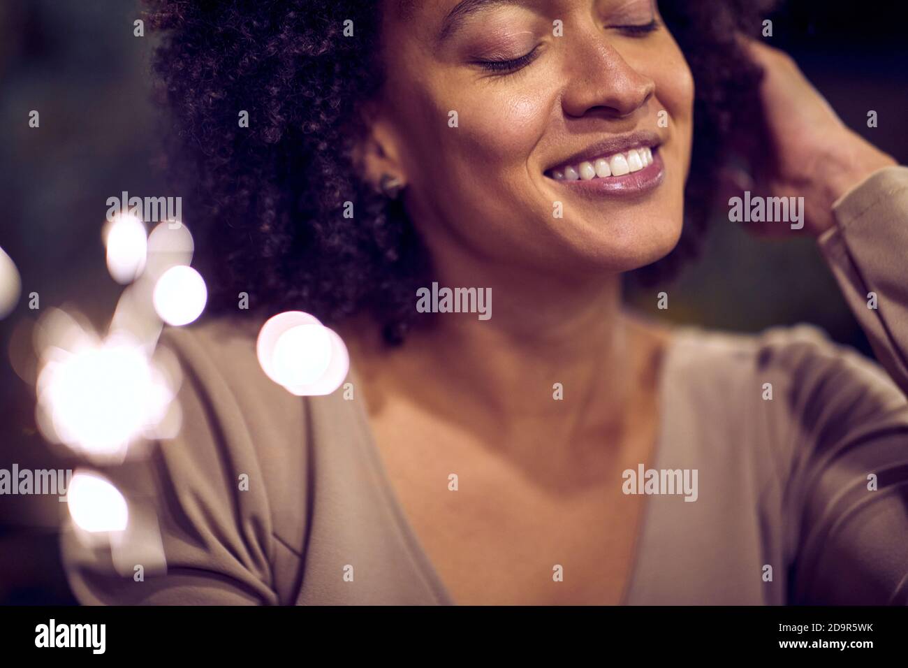 Porträt einer glücklichen jungen afroamerikanischen Frau mit angezündeten Händen Funkeln Stockfoto