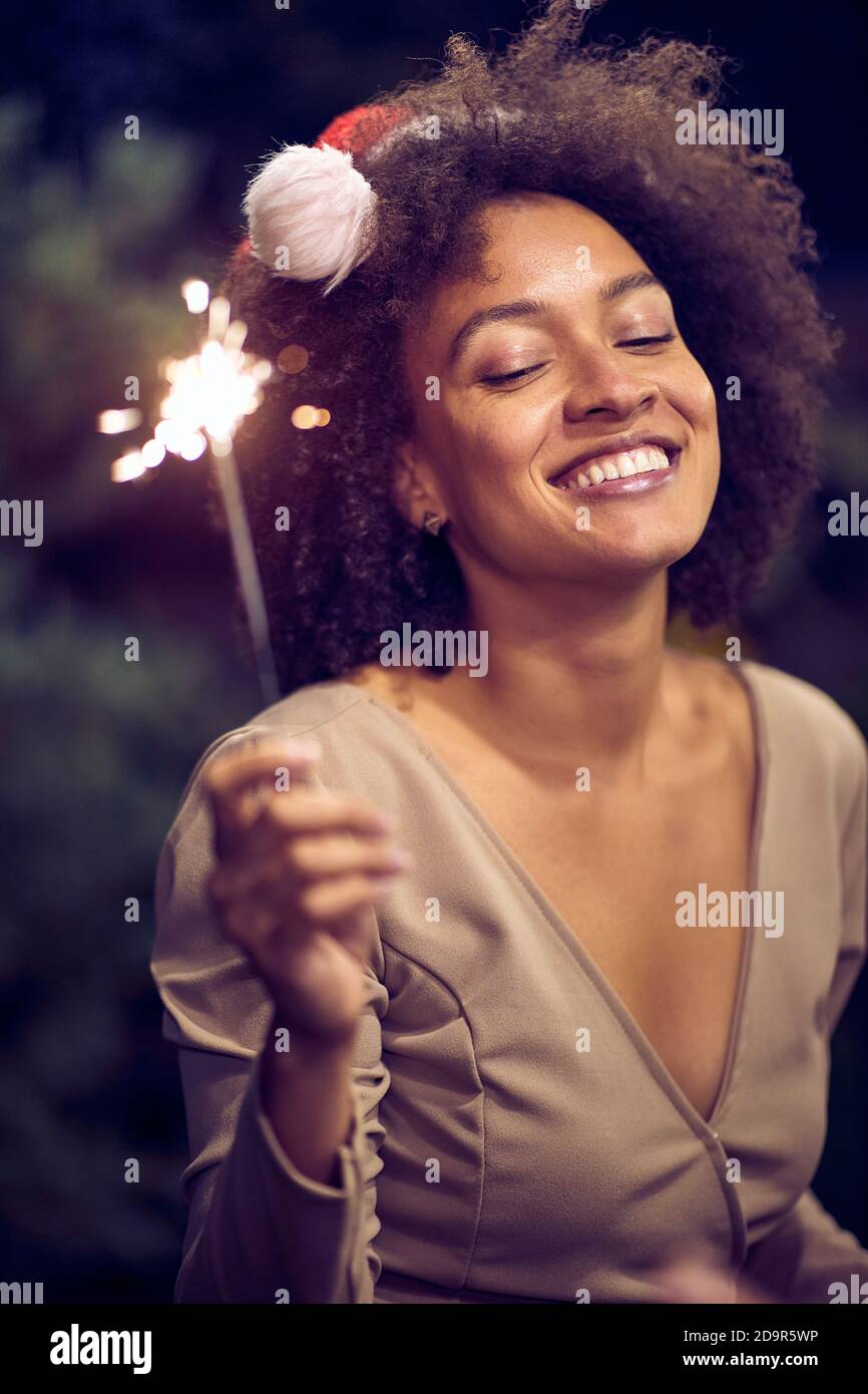 Porträt einer glücklichen jungen afroamerikanischen Frau mit angezündeten Händen Funkeln Stockfoto