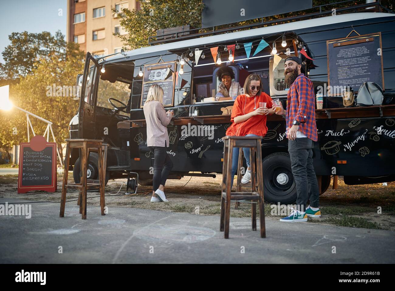 Hipster mit Freunden vor modifiziertem LKW für mobile Fastfood-Service mit Blick auf die Kamera Stockfoto