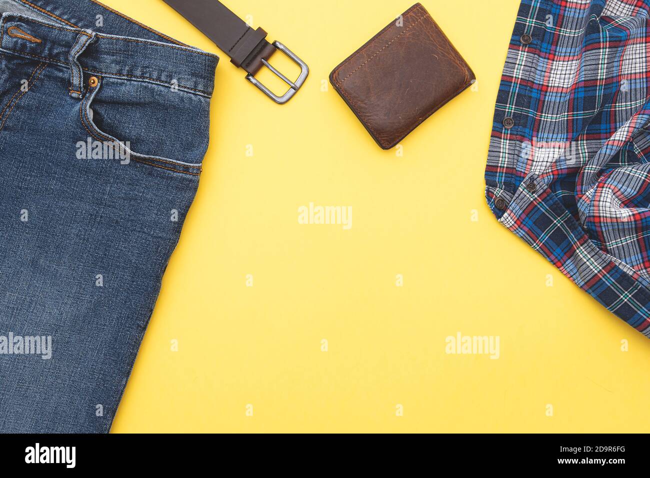 Mode Hintergrund, Jeans, Hemd, Gürtel, Geldbörse. Denim-Style. Draufsicht. Männer Kleidung auf gelbem Hintergrund, Platz für Text. Stockfoto