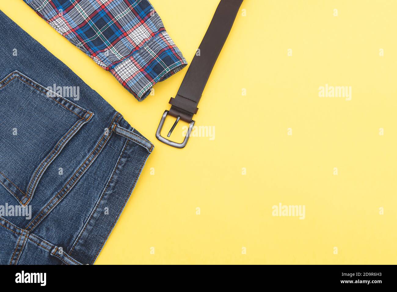 Mode Hintergrund, Jeans, Hemd, Gürtel. Denim-Style. Draufsicht. Männer Kleidung auf gelbem Hintergrund, Platz für Text. Stockfoto