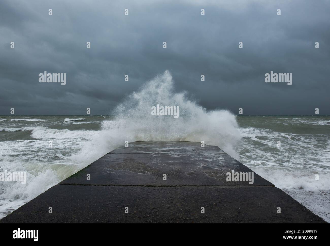 Wellenspritzer gegen Betongroyne während gelber Wetterwarnung in Brighton, England Stockfoto