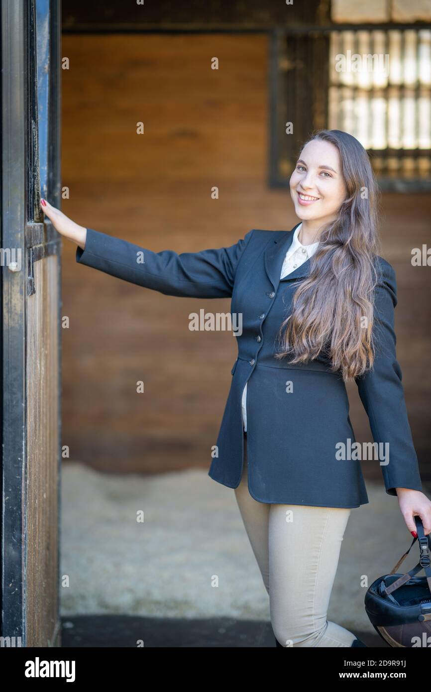 Reiterin Frau in englisch Reiten vor Stalltür stehend gekleidet Stockfoto