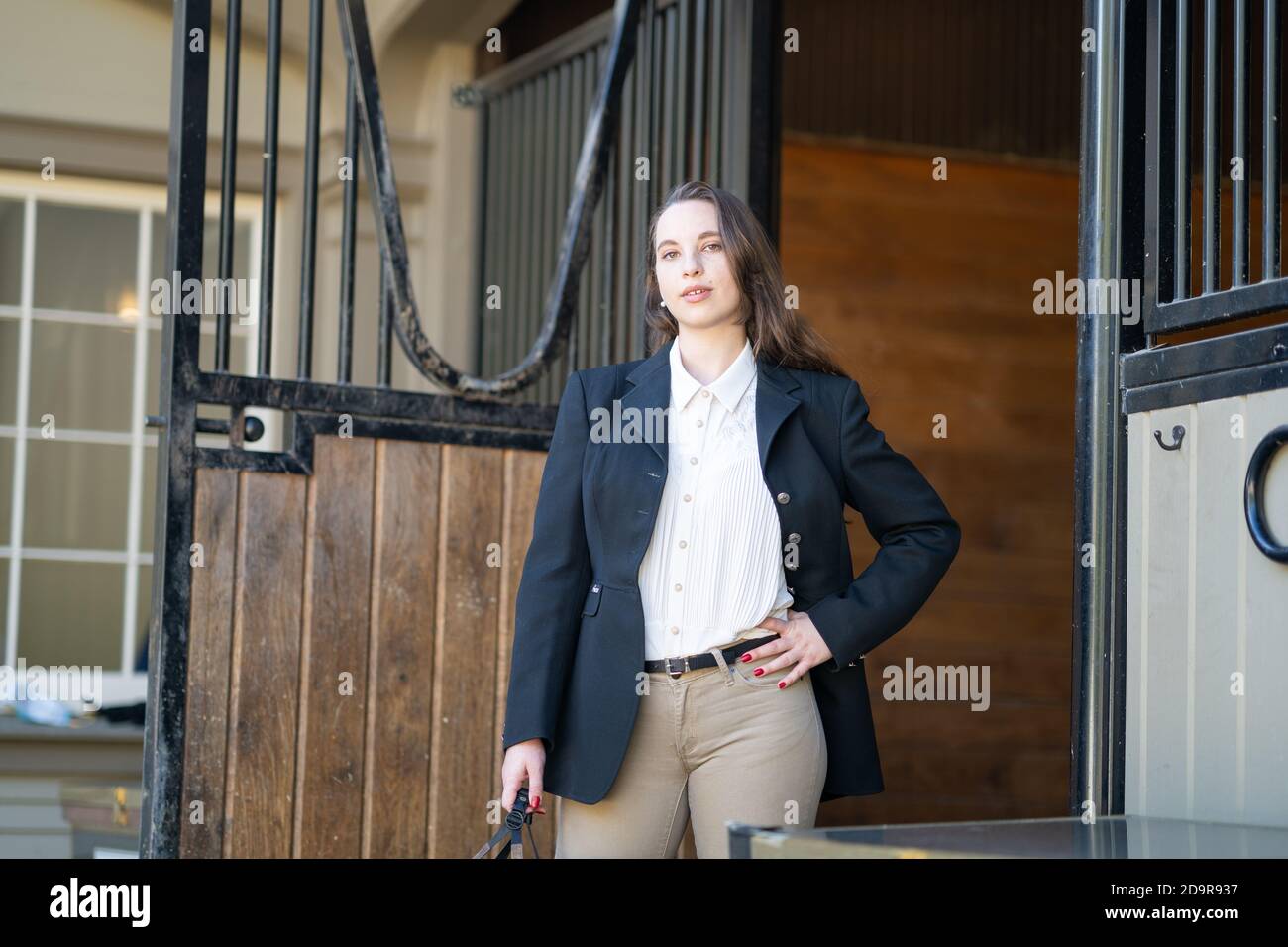 Reiterin Frau in englisch Reiten vor Stalltür stehend gekleidet Stockfoto