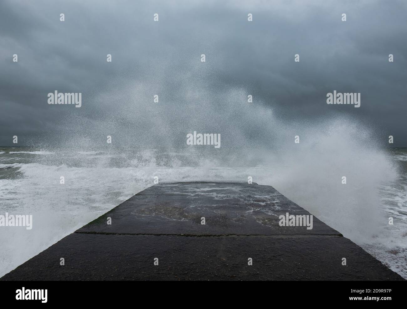 Wellenspritzer gegen Betongroyne während gelber Wetterwarnung in Brighton, England Stockfoto