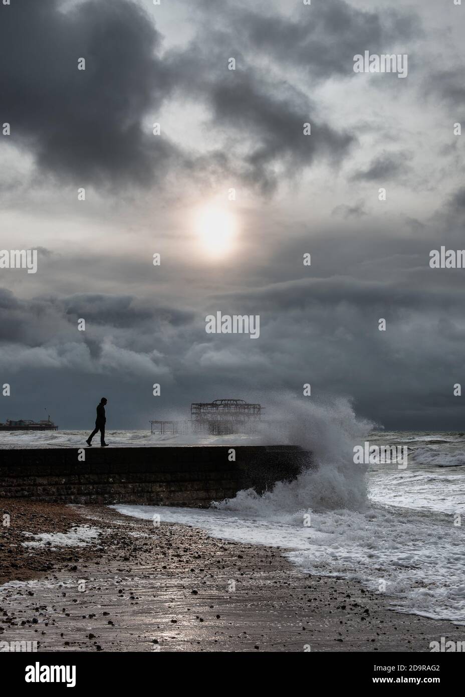 Ein Mann, der bei stürmischem Wetter in Brighton auf Groyne läuft, Großbritannien Stockfoto