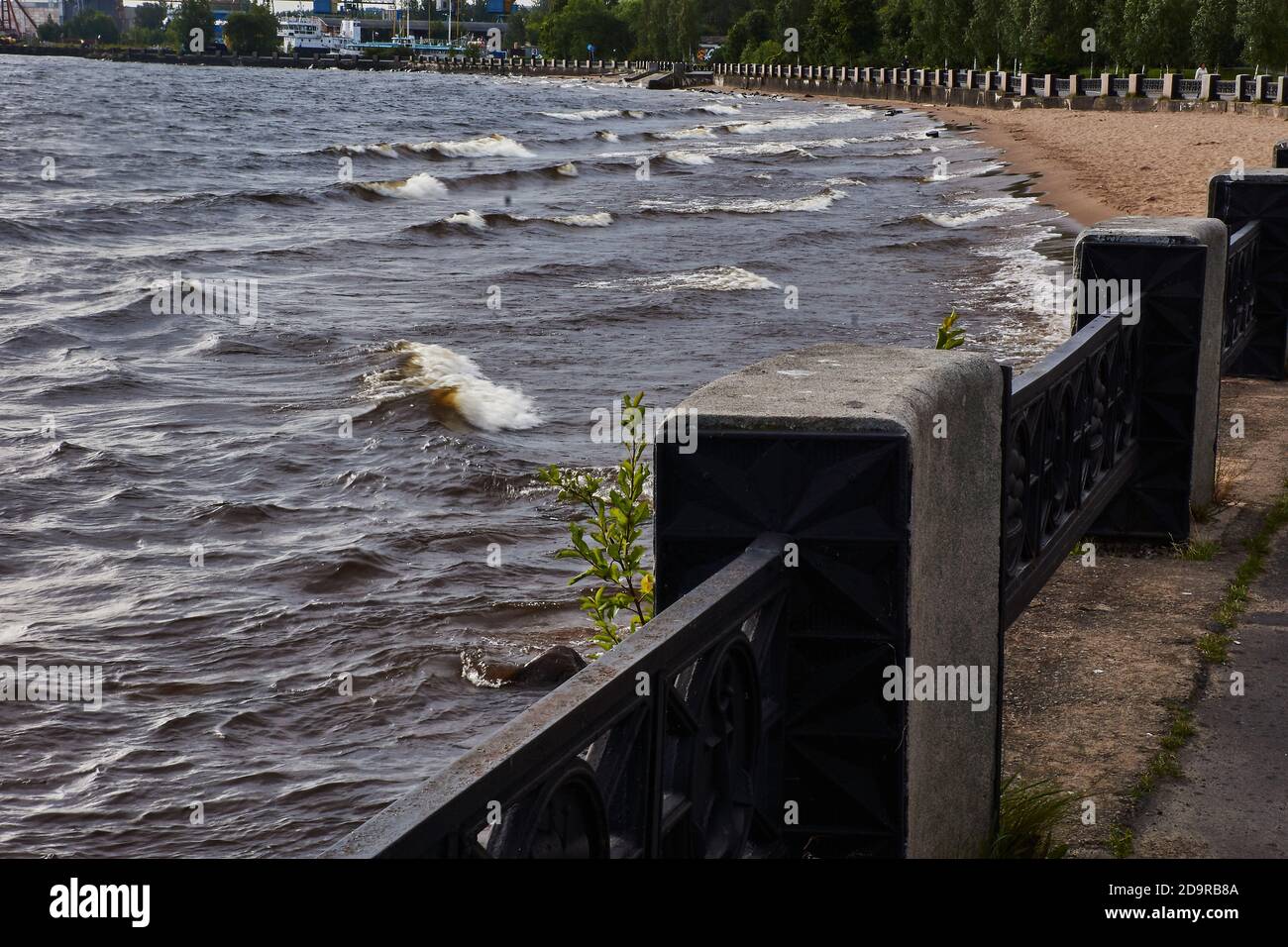 Am sandigen Ufer des Sees befindet sich ein Granitdamm, der mit einem gusseisernen Zaun mit Sockeln eingezäunt ist. Auf dem See erhob sich der Wind Stockfoto