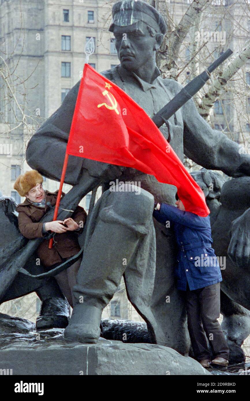 Kommunistische Anhänger besteigen eine Statue, die an den Aufstand gegen das zaristische Regime von 1905 erinnert, um die Flagge der UdSSR während der Anti-Jelzin-Proteste vor dem russischen parlamentsgebäude am 1. März 1993 in Moskau, Russland, zu hissen. Das russische Parlament stimmt darüber ab, ob es Präsident Boris Jelzin entheben soll. Stockfoto