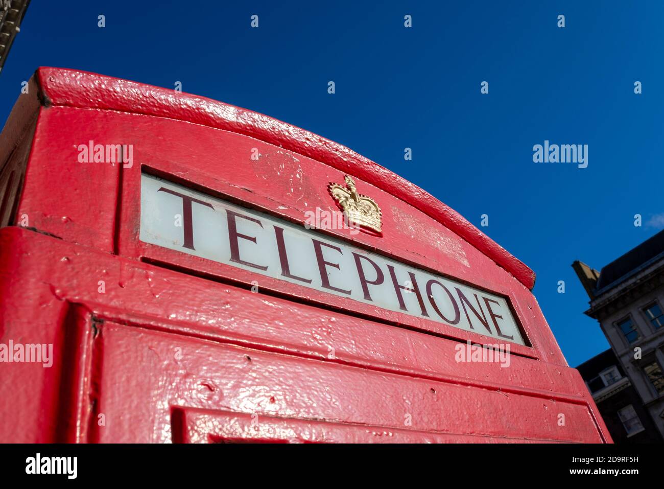 Detail einer roten Londoner Telefonbox. Rote Telefonbox Schriftzug und königliches Wappen. In Whitehall, Westminster, London, Großbritannien, in hellblauem Himmel Herbsttag Stockfoto