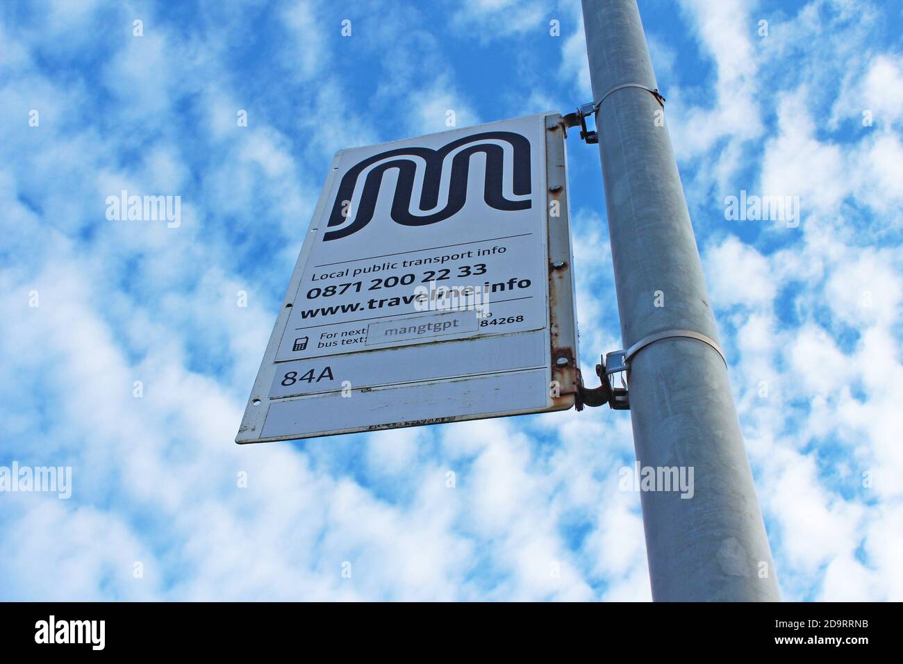 Bushaltestelle Schild uk auf einer Stange mit einem blauen Himmel und Wolken in Manchester, England Stockfoto