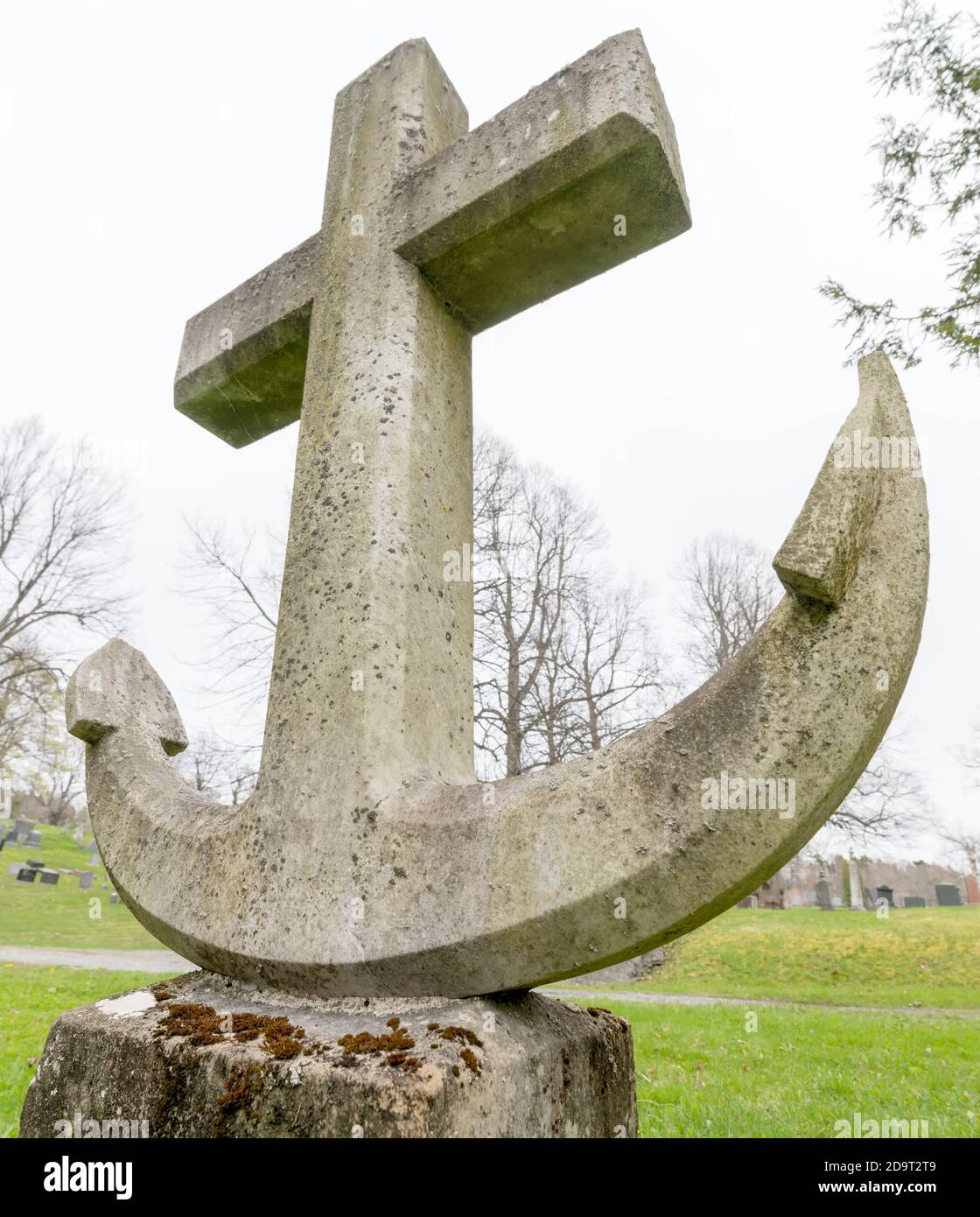 Ein Grabstein in Form eines Schiffsankers. Es ist kein Text vorhanden. Dies ist eine Ansicht mit niedrigem Winkel, die nach oben zeigt. Es gibt etwas Moos auf dem Grabstein. Stockfoto