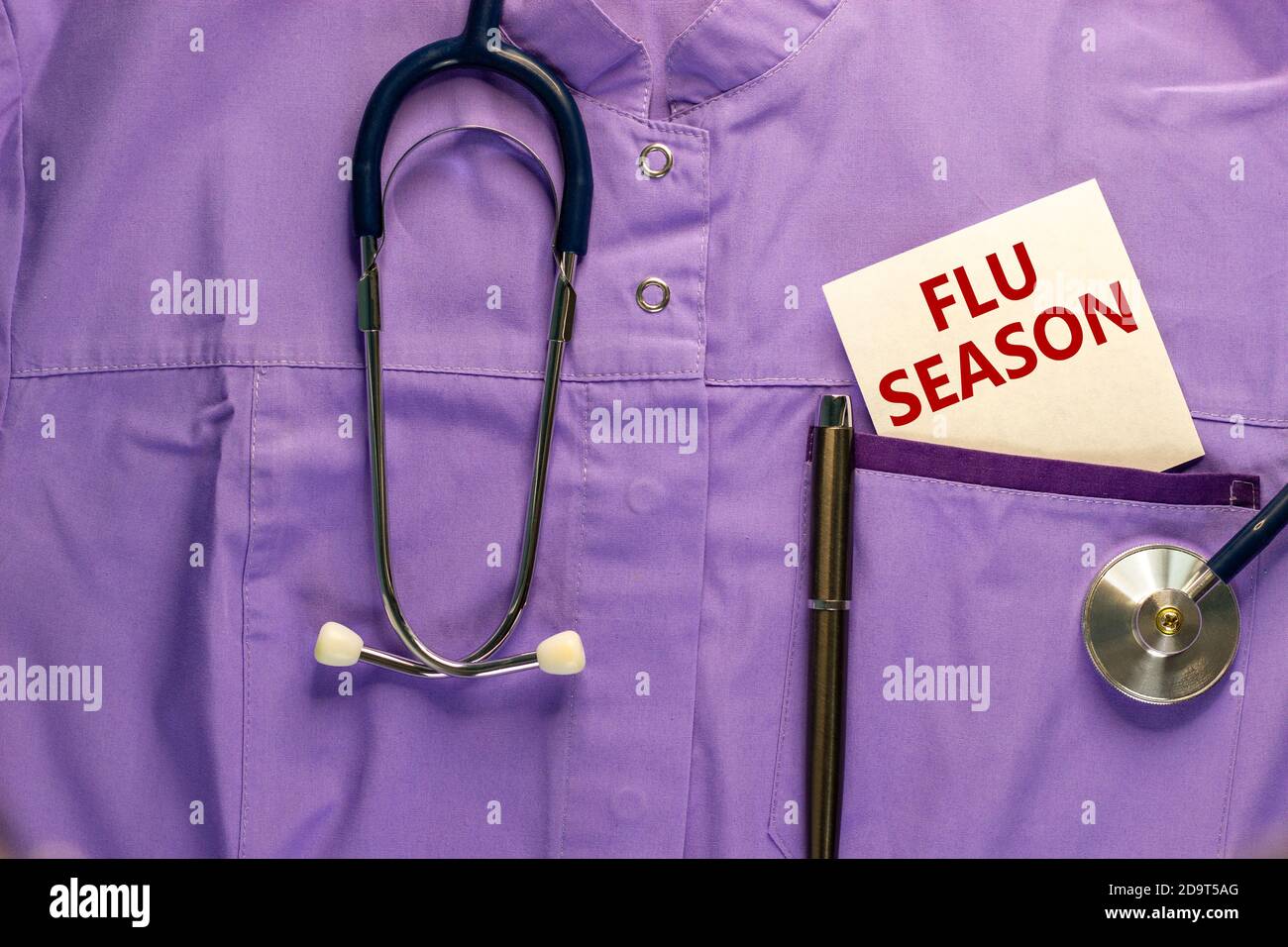 Medizinische Uniform, weiße Karte mit Worten Grippesaison, Metallstift und Stethoskop. Medizinisches Konzept. Stockfoto
