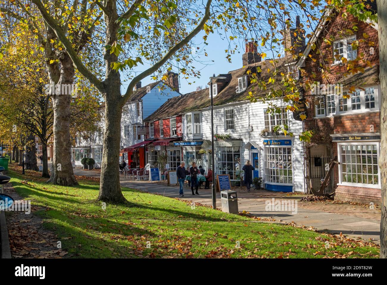 Das breite Bürgersteig der Tenterden High Street mit Geschäften und Cafés mit Menschen essen in Autumn Sunshine, Kent, UK, GB Stockfoto