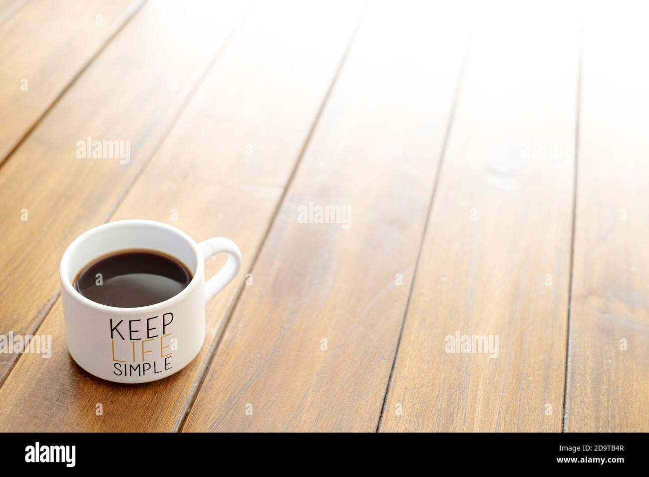 Kaffeetasse auf einem Holztisch mit einer Botschaft von Halten Sie das Leben einfach Hintergrund Stockfoto