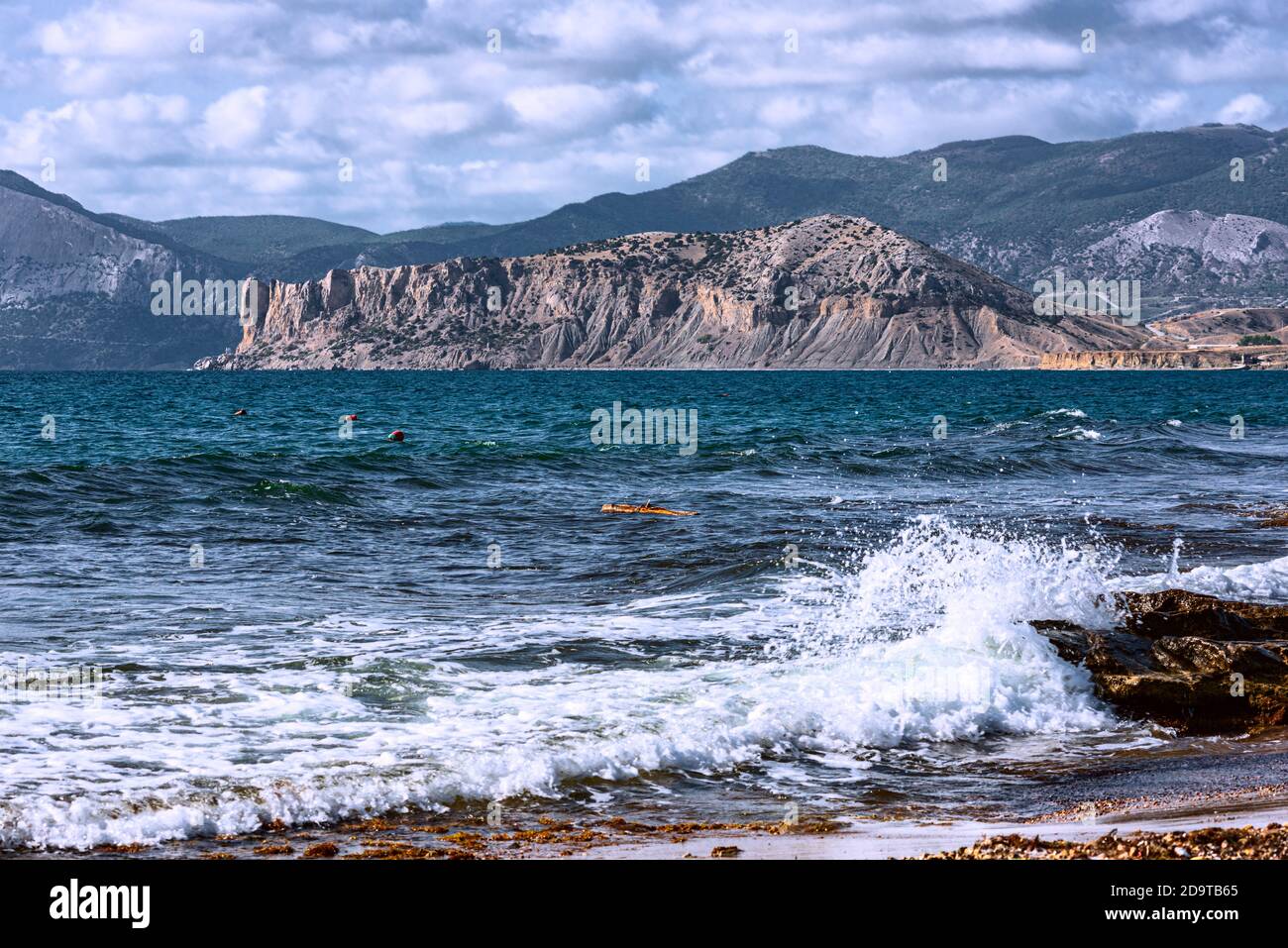 Das Meer ist rauh und der Wind weht. Wellen Rollen auf dem felsigen Ufer, Cumulus Wolken am Himmel. Die Bucht in der Nähe des Dorfes Almond ist umgeben b Stockfoto