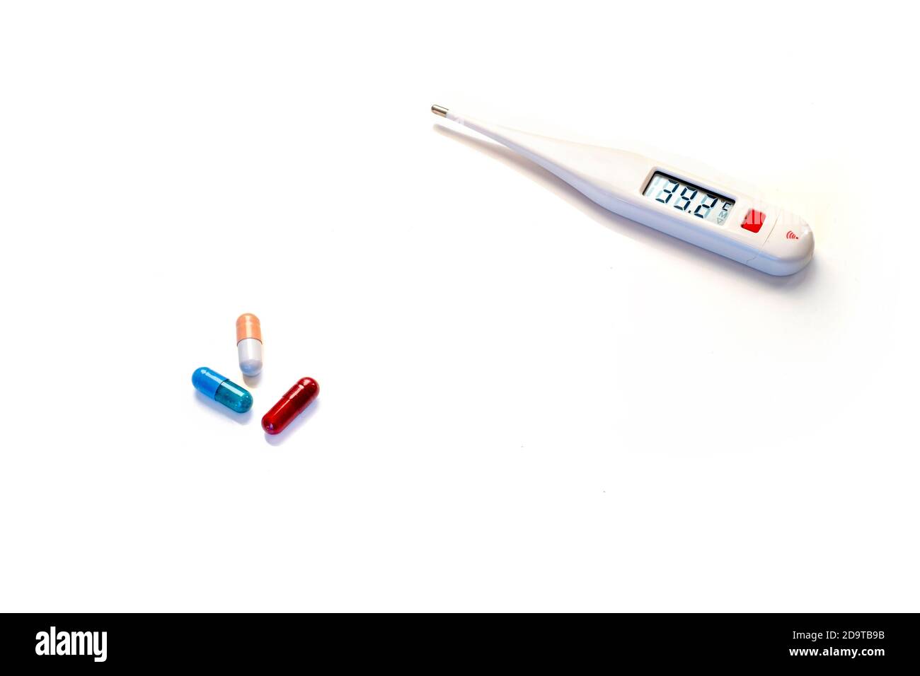 Digitalthermometer mit Fieberwerten und mehrfarbigen Tabletten Weißer Hintergrund Stockfoto