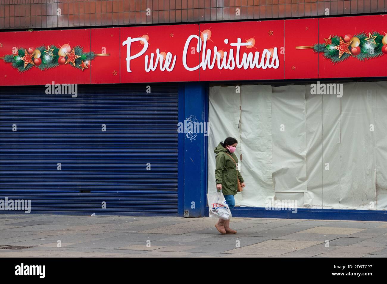 Ein Mitglied der Öffentlichkeit kommt während der Coronavirus-Pandemie im November 2020 an einem geschlossenen „reinen weihnachtsgeschäft“ in Glasgow, Schottland, Großbritannien vorbei Stockfoto