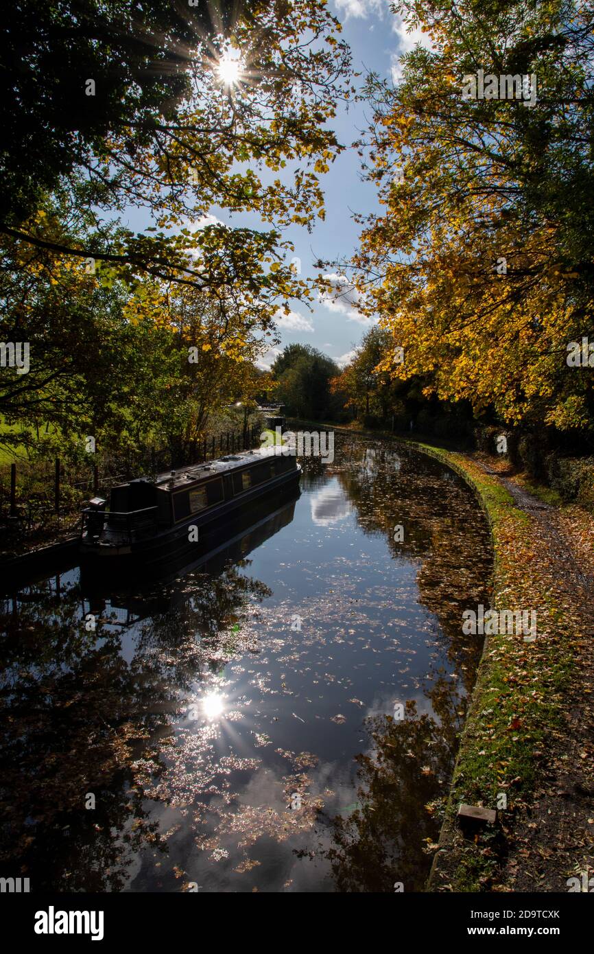 Ein Kanal mit den Herbstfarben in den Bäumen und Das stilles Wasser der historischen Kanäle von Dudley mit Ein Kanalboot dockte an der Seite an Stockfoto