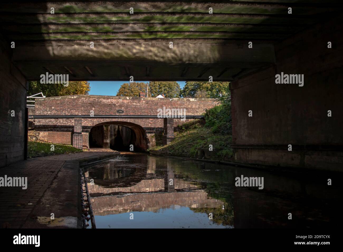 Eine alte Brücke unter einer Brücke mit dem Spiegelung des Wassers auf den Brücken Dach mit dem Kanal unten Stockfoto