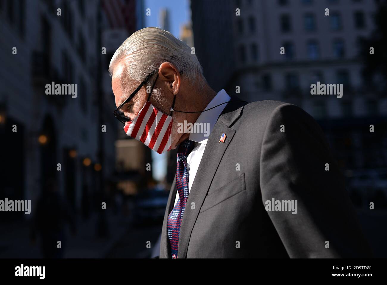 New York City, USA. November 2020. Ein Sicherheitsmann für Bergdorf und Goodman trägt eine Maske mit amerikanischer Flagge, als er in Richtung Massen geht, die vor dem Trump Tower auf der 5th Ave. Feiern, nachdem die Medien Joe Biden zum Gewinner der US-Präsidentschaftswahlen 2020 erklärt haben, New York, NY, 7. November 2020. Der Demokrat Joe Biden besiegte Präsident Donald Trump, um der 46. Präsident der Vereinigten Staaten zu werden, nachdem berichtet wurde, dass Biden Pennsylvania mit 20 Wählerstimmen gewann.“ (Anthony Behar/Sipa USA) Quelle: SIPA USA/Alamy Live News Stockfoto