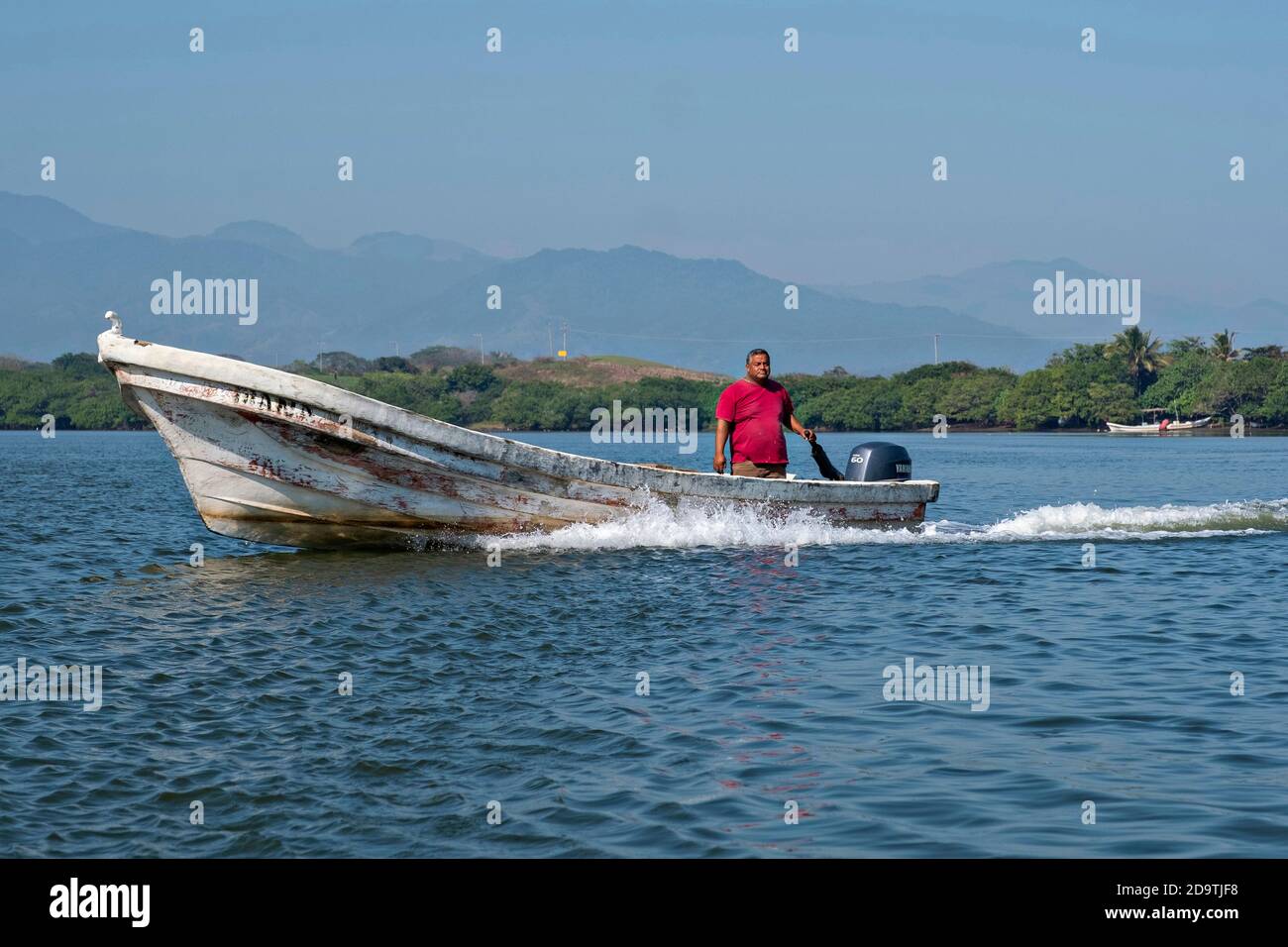 Ein Fischer motort seinen Panga in Lake Catemaco, Veracruz, Mexiko. Die Lagune, die in den Golf von Mexiko mündet, ist eines der am besten erhaltenen Feuchtgebiete und Mangrovenwälder in Mexiko und Teil des Biosphärenreservats Los Tuxtlas. Stockfoto