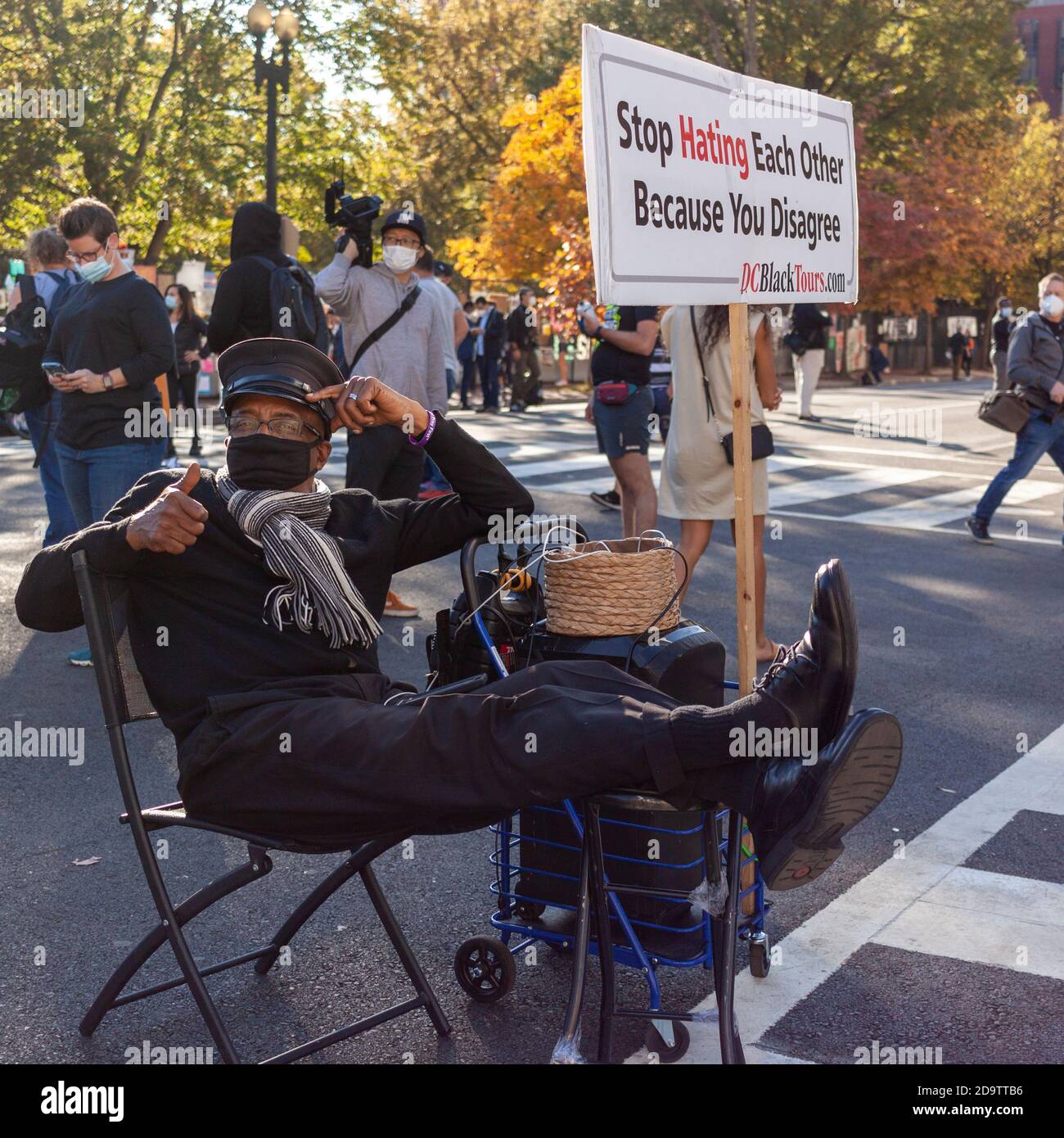 Washington DC, USA 11/06/2020: Ein älterer afroamerikanischer Mann sitzt neben einem Transparent, auf dem steht: "Stop hassing each other because you disagree" A n Stockfoto