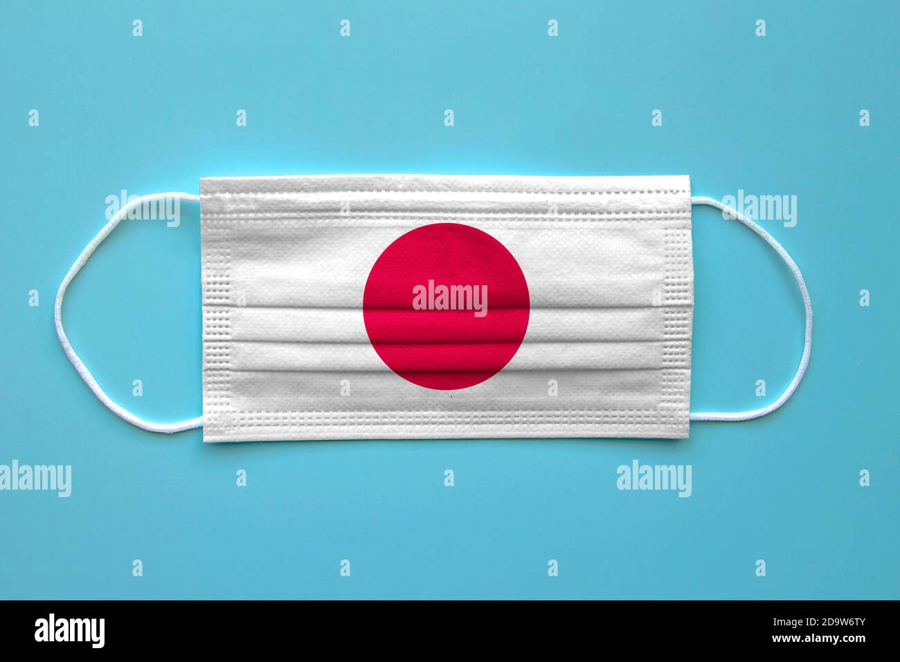 Eine Gesichtsmaske mit japanischer Flagge auf klarem Hintergrund. Konzept: Japan während der Pandemie. Stockfoto
