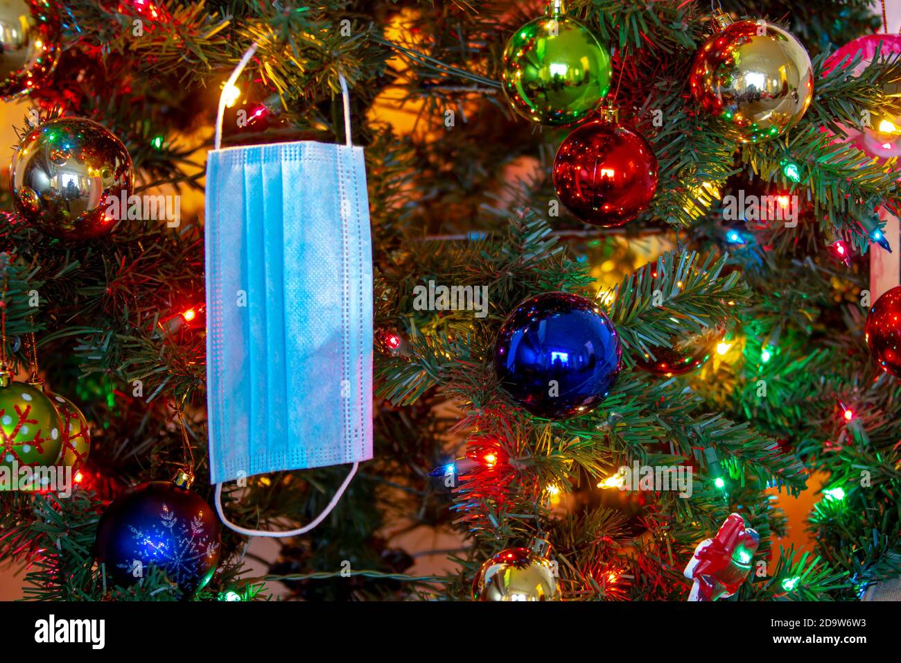 Eine medizinische Gesichtsmaske, die an einem Weihnachtsbaum hängt. Konzept: Pandemie, covid -19, Coronavirus während der Weihnachtsfeiertage Stockfoto