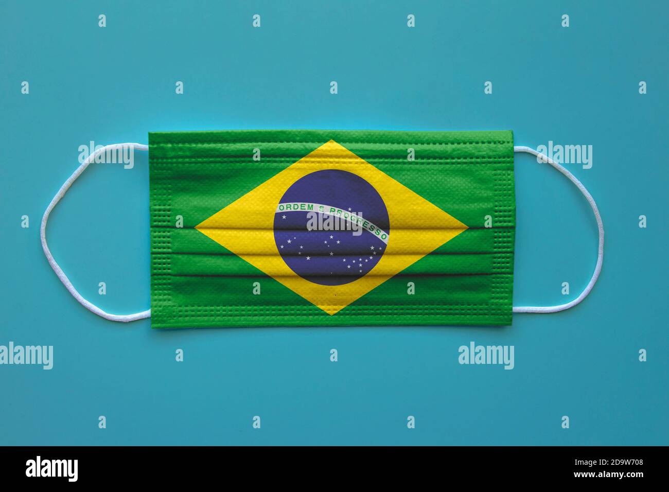 Eine Gesichtsmaske mit brasilianischer Flagge auf klarem Hintergrund. Konzept: Brasilien während der Pandemie. Stockfoto