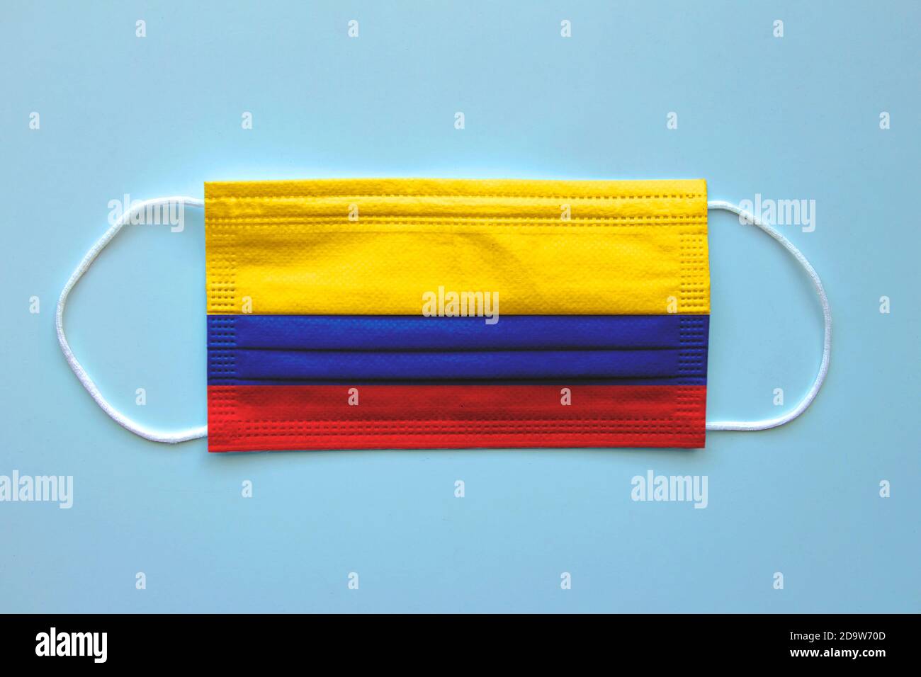 Eine Gesichtsmaske mit kolumbianischer Flagge auf klarem Hintergrund. Konzept: Kolumbien während der Pandemie. Stockfoto