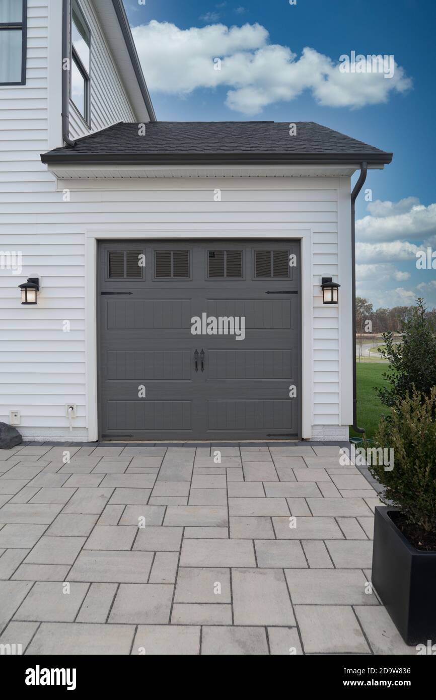 Graues Einzelgaragentor für Familien mit dunklen, weißen Wänden und Garagentor-Lampen Stockfoto