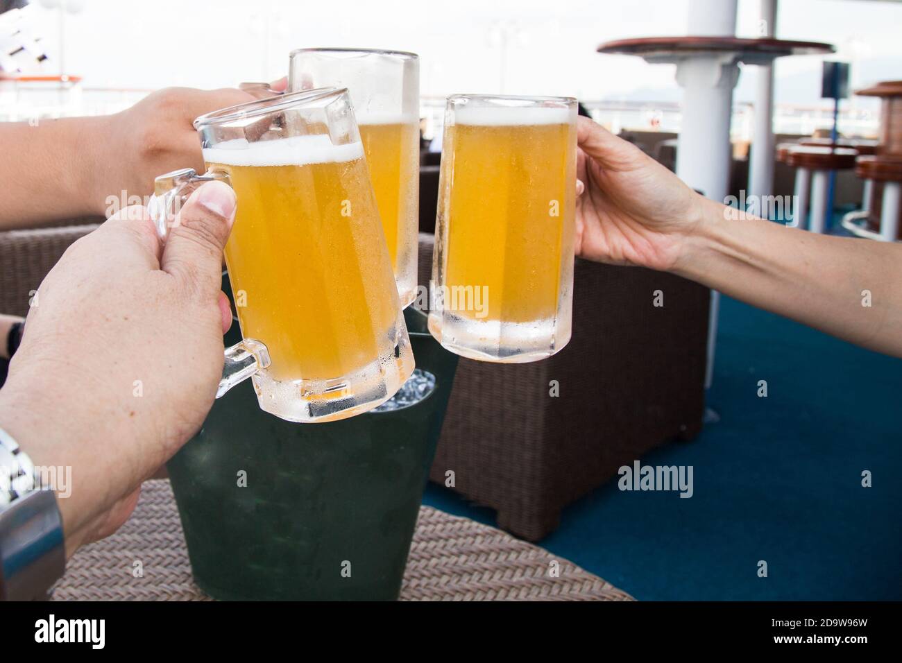 Drei Personen klopfen Biergläser an, um in der Feier zu toasten Stockfoto