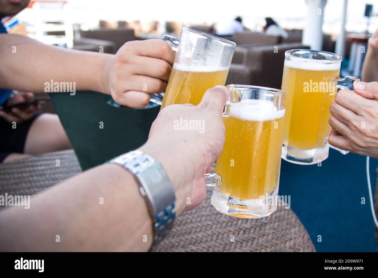 Drei Personen klopfen Biergläser an, um in der Feier zu toasten Stockfoto