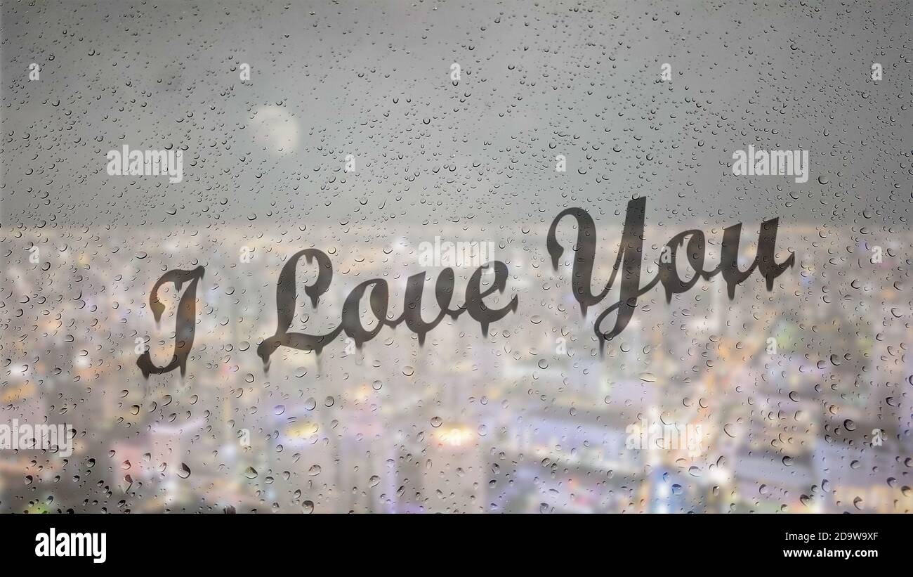 Zeichnen Sie Buchstaben, die ich liebe Sie von Hand auf einem Glas mit Wassertropfen Tropfen mit Nacht Stadtbild Hintergrund. Stockfoto