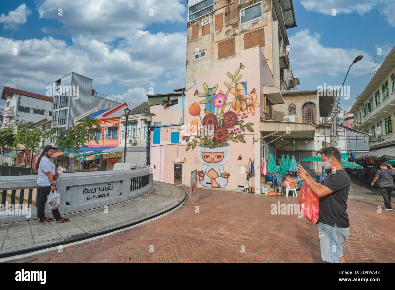 Ein Paar fotografiert ein Wandgemälde des thailändischen Künstlers Alex Face mit seiner dreiäugigen Figur Mardi Meditierende; Phahurat / Chinatown Bangkok, Thailand Stockfoto