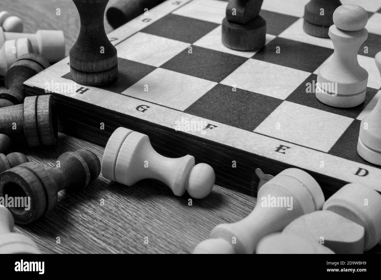 Ende des Schachspiels, Schachfiguren liegen in der Nähe des Schachbretts auf dem Tisch, Draufsicht, schwarz und weiß. Stockfoto