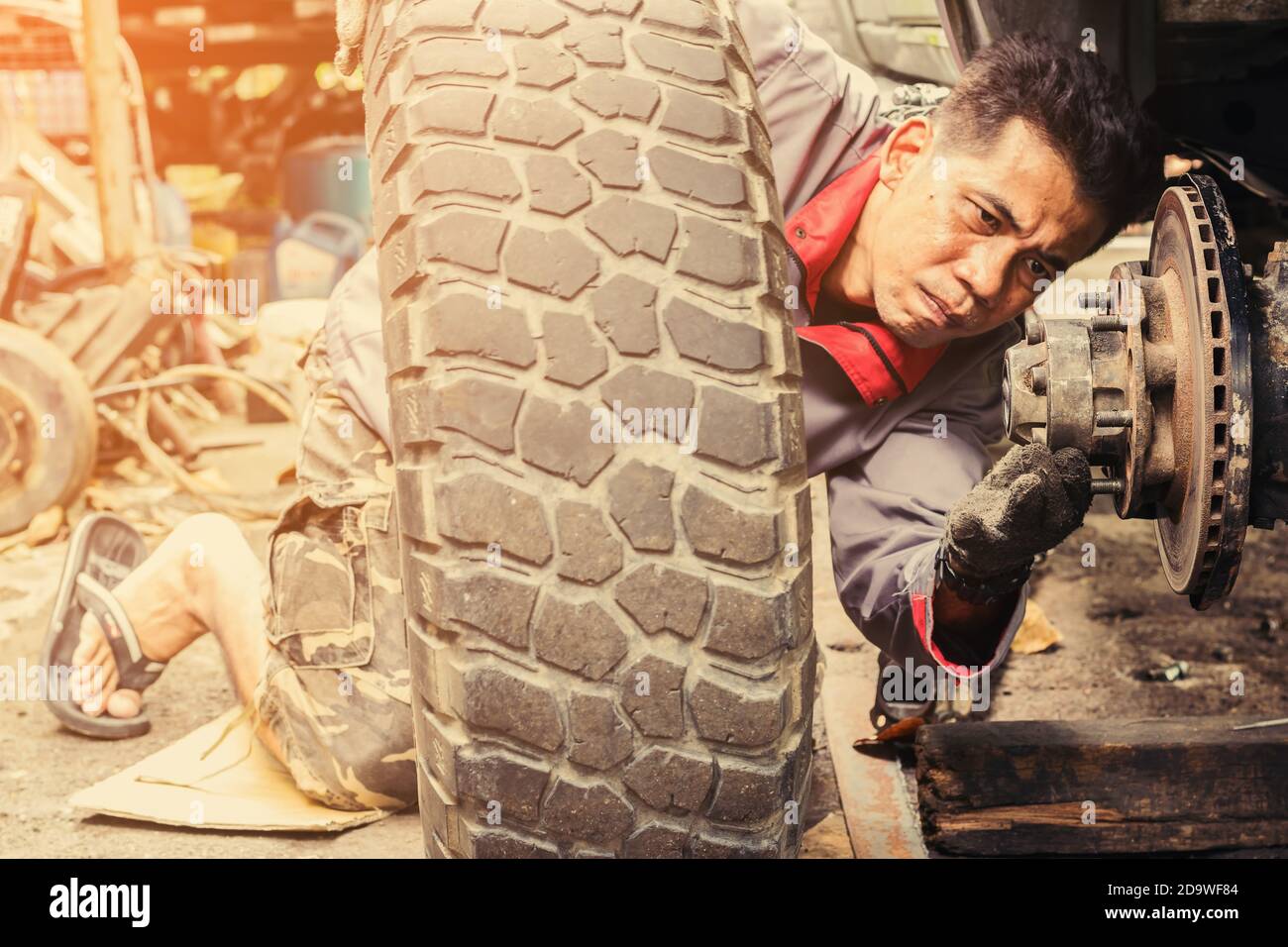 Der Techniker setzt die Räder des Fahrzeugs nach dem Ausbau wieder ein, um die Bremsen zu reparieren. Stockfoto