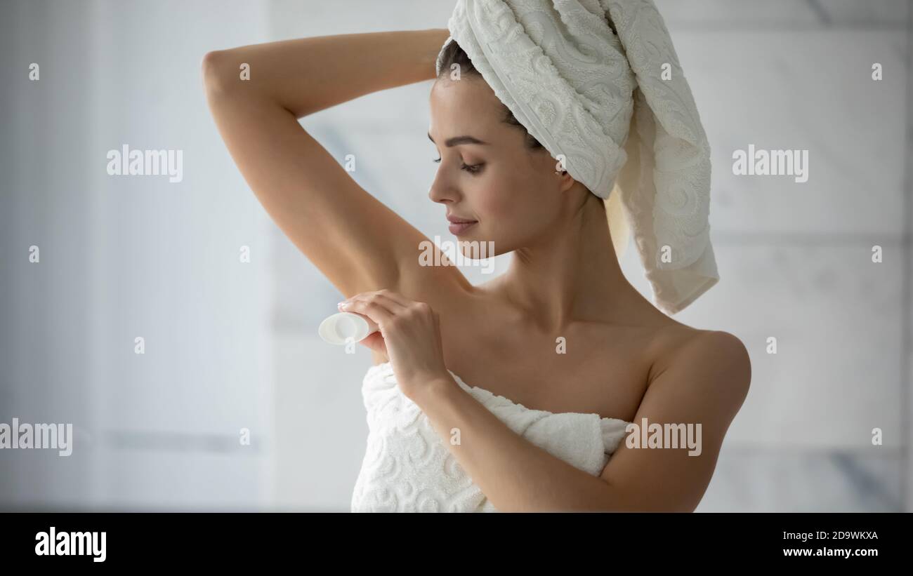 Hübsche Millennial weiblich in Handtuch gewickelt setzen Deodorant auf Achselhöhle Stockfoto