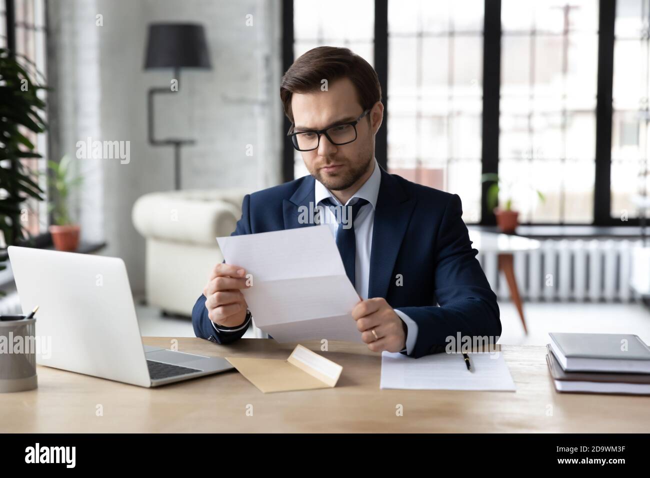 Serious 30er männlichen Manager in Anzug Lesen Postkorrespondenz Brief. Stockfoto