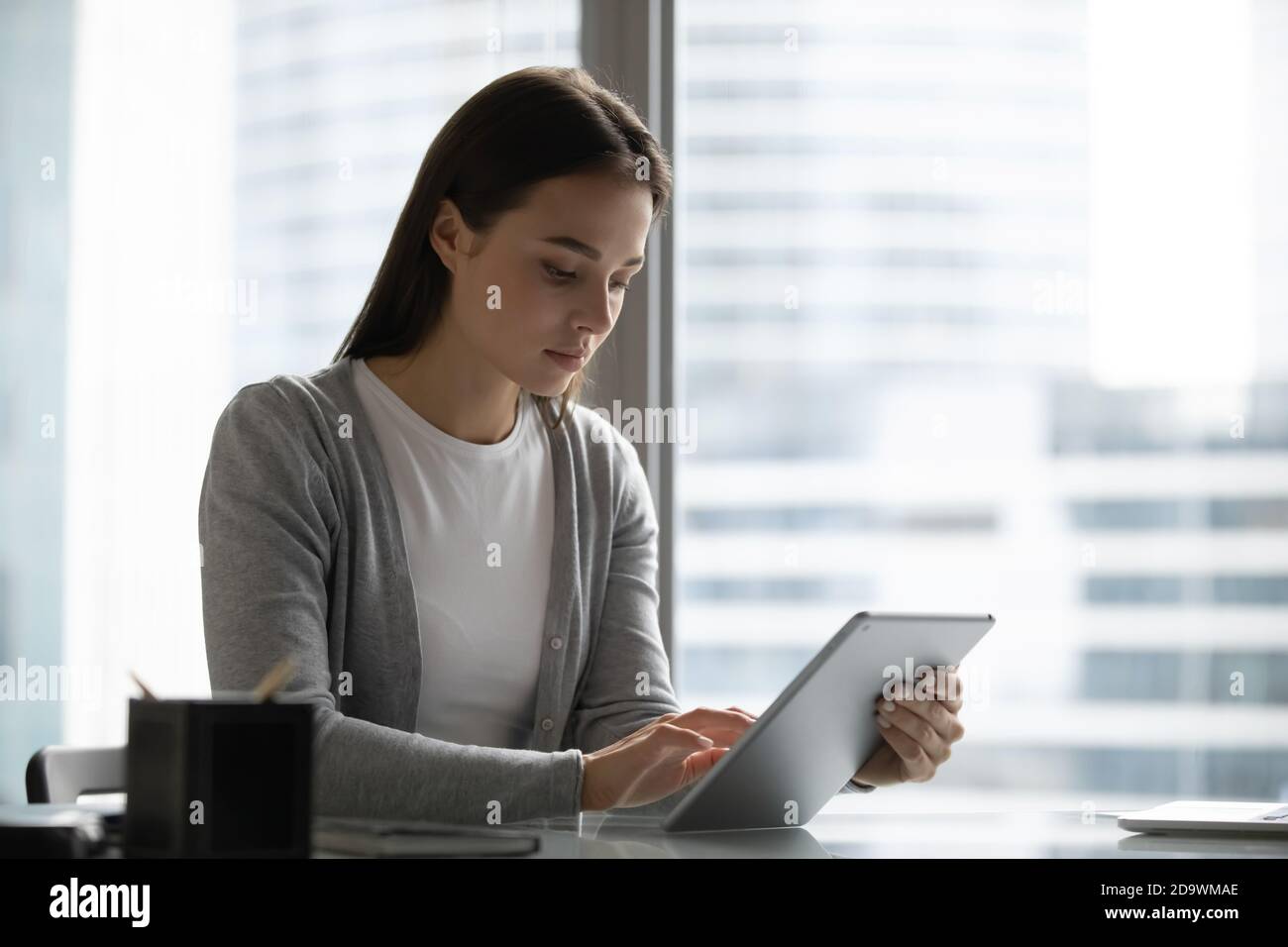 Millennial Managerin sitzt am Schreibtisch und arbeitet am Tablet-pc Stockfoto