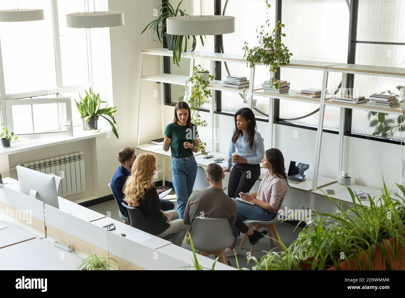 Gruppe von verschiedenen Mitarbeitern, die der Teamleiterin der Millennial-Frau zuhören Stockfoto