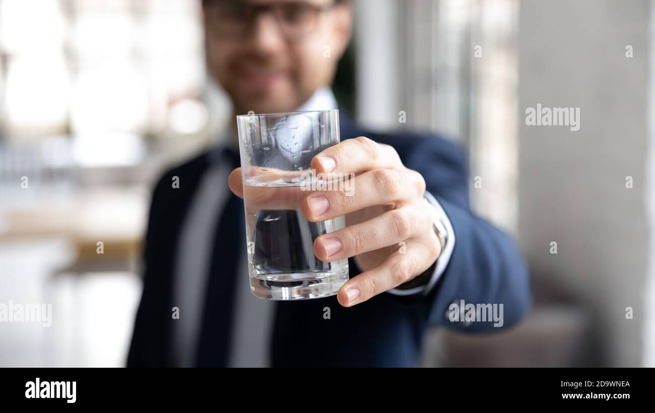 Junger Unternehmer, der mit einem Glas Wasser die Hand ausstreut. Stockfoto