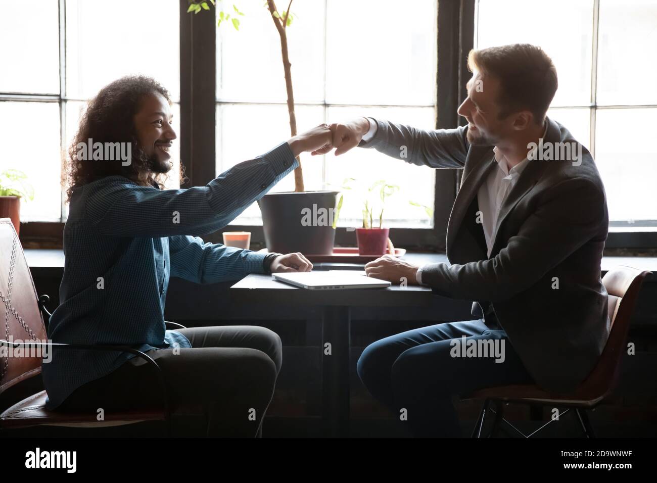 Zwei verschiedene Männer Freunde stoßen Fäuste über Tisch im Kaffeehaus Stockfoto