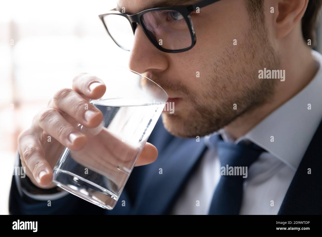Junger Geschäftsmann in Brillen trinken Glas von frischem Wasser. Stockfoto