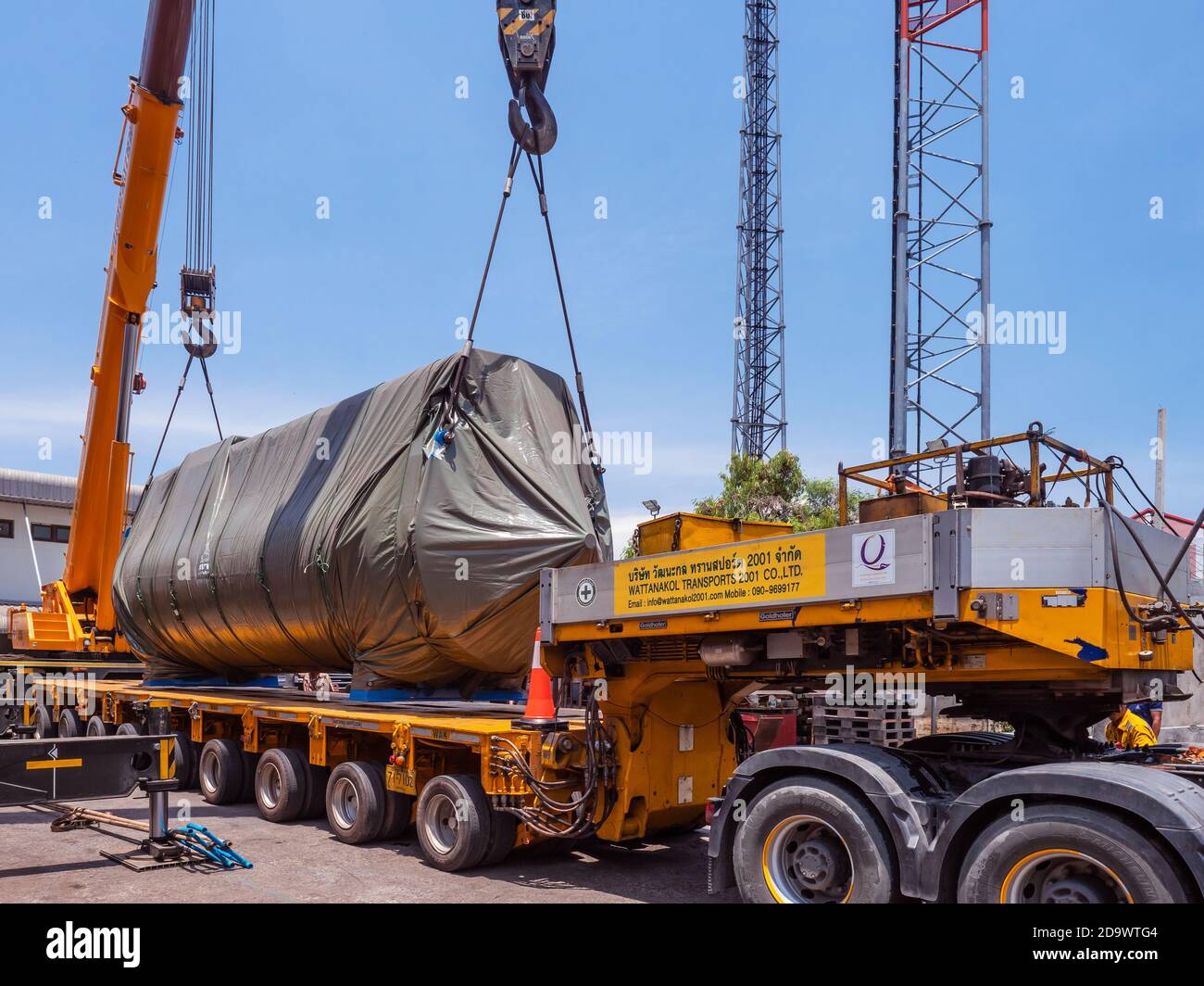 LKW für Schwertransporte und zwei große Mobilkrane laden einen großen Industrietrockner für den Versand in einer Industriewerkstatt in Samut Prakan, Thailan Stockfoto