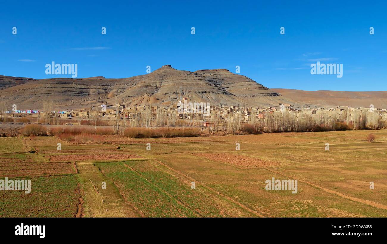 Panoramablick auf kleines Berberdorf mit Lehmbauten in der Nähe von Imilchil, Marokko, Afrika im Atlasgebirge mit grünen Feldern. Stockfoto