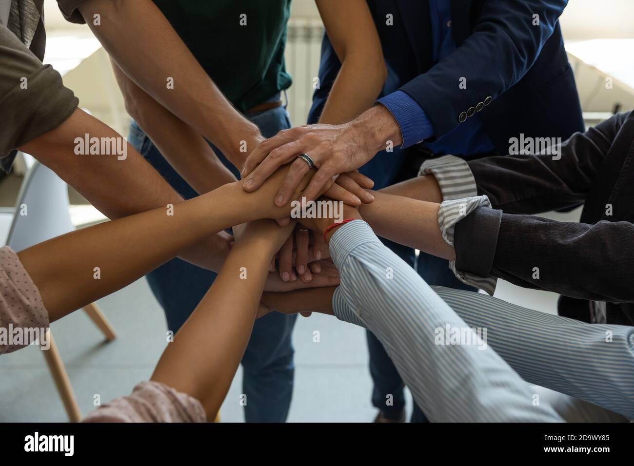 Motivierte verschiedene Geschäftsleute, die Hand zusammenlegen und Einheit demonstrieren Stockfoto