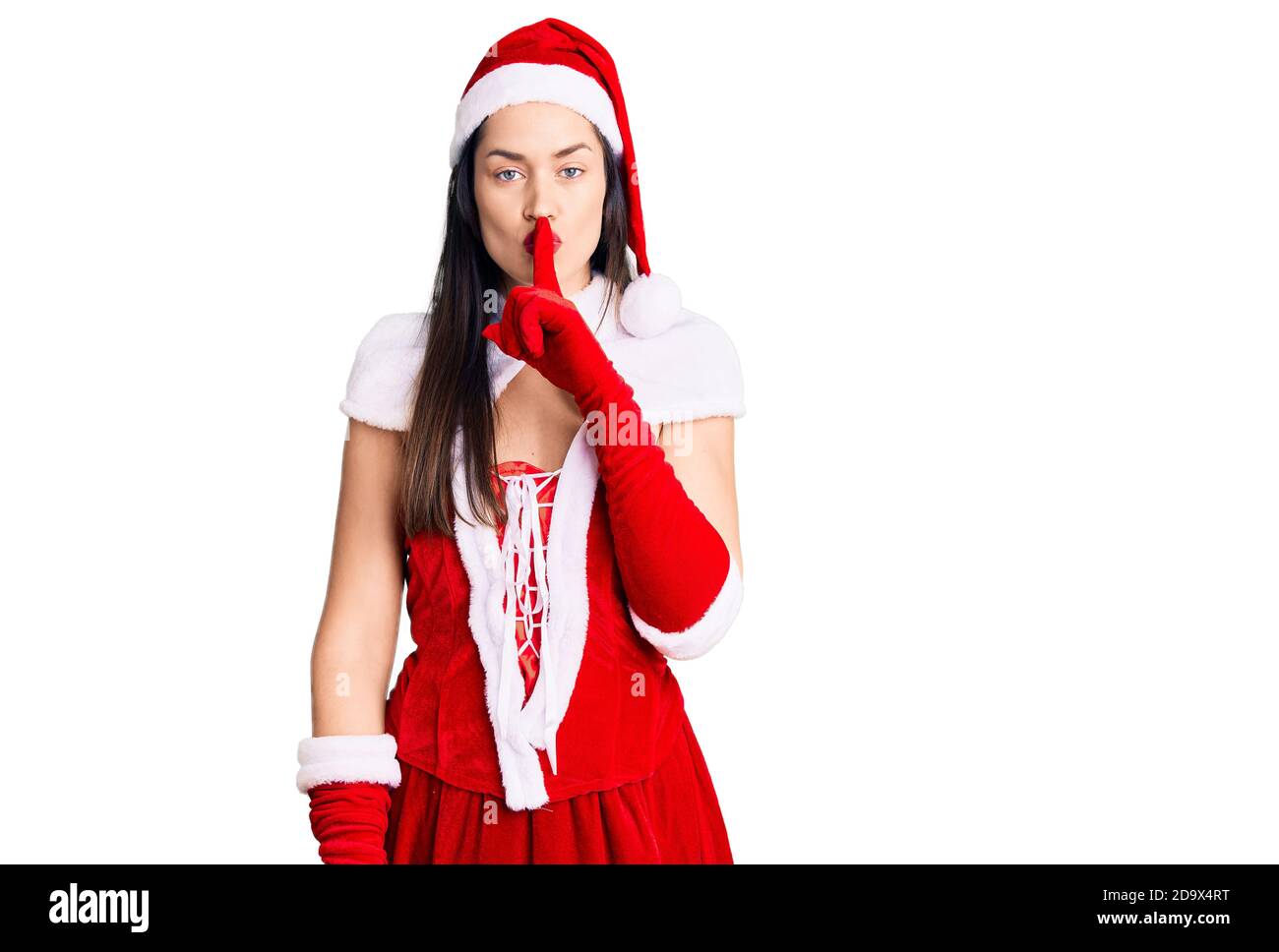 Junge schöne kaukasische Frau trägt weihnachtsmann Kostüm bitten, ruhig mit Finger auf den Lippen zu sein. Stille und geheime Konzept. Stockfoto