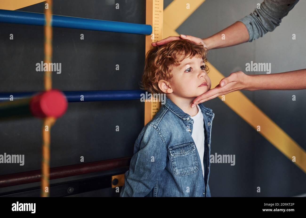 Lehrer, der die Höhe des Kindes im Kindergarten misst Stockfotografie