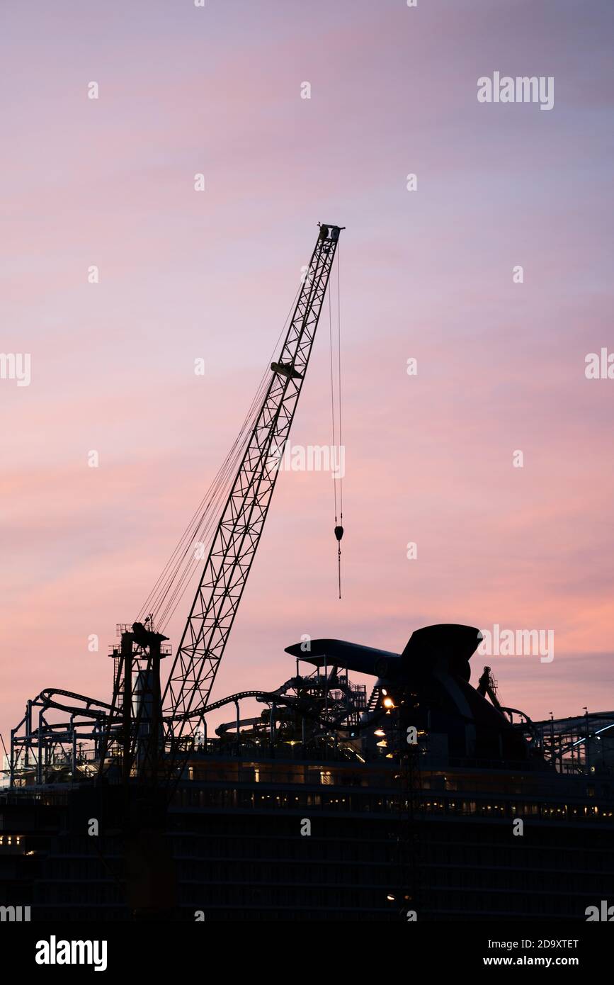 Silhouette eines Baukran und Oberteil eines Kreuzfahrtschiff im Morgengrauen Stockfoto